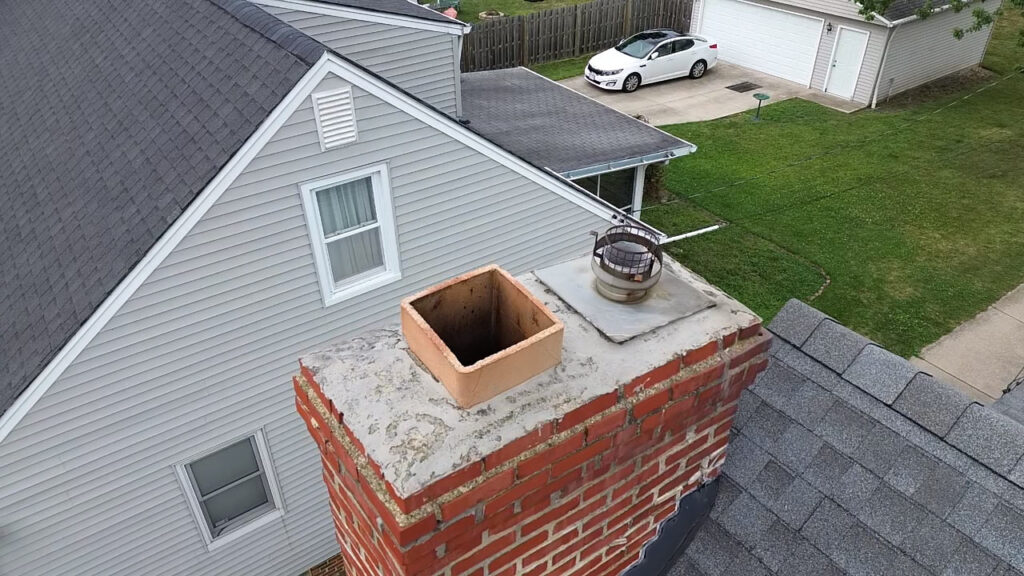 Chimney Sweep Cost: What You Should Expect to Pay 2 Aerial view of a brick chimney crown, clay flue tile and chimney cap on a Cleveland area roof
