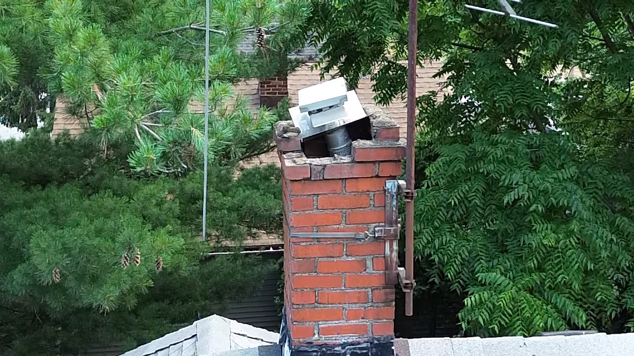 Why Is My Chimney Leaking When It Rains? The 5 Usual Causes in Cleveland Homes 1 Brick chimney topped with a smooth gray crown sloping from the flue to the brick edge, with a stainless steel chimney cap and mesh screen on top